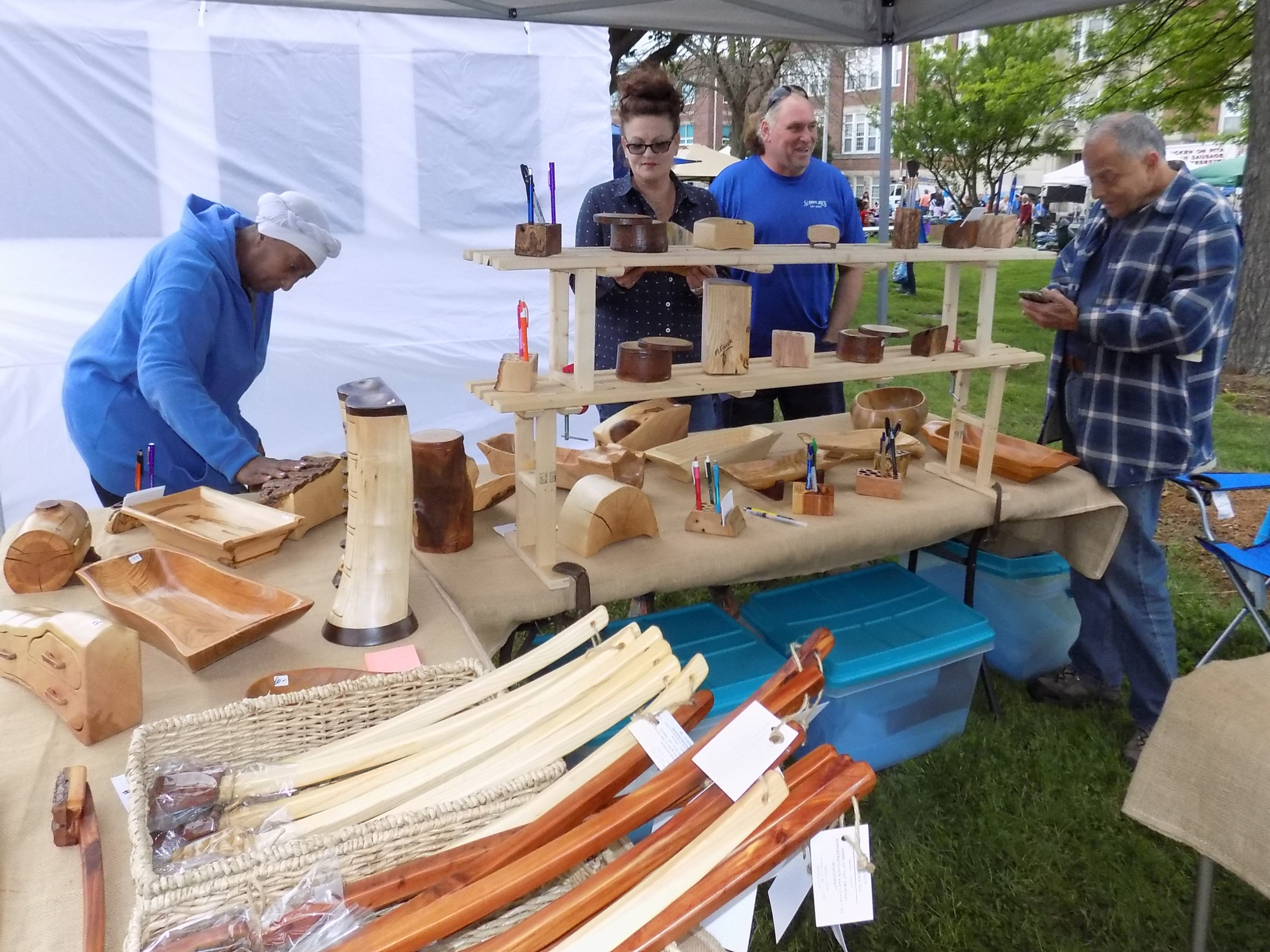 Vendors behind a craft table selling handmade wood items